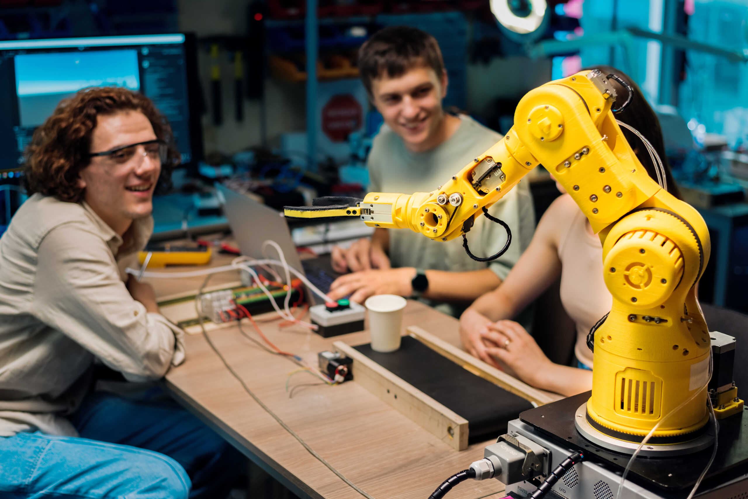 Group of young people doing experiments in robotics in a laboratory. Robot and tools on the table